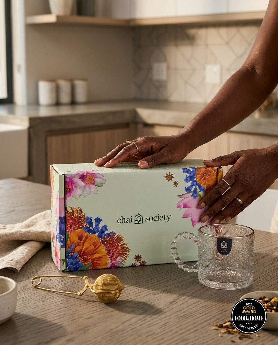 Hands resting on a Chai Society tea gift box in a home kitchen