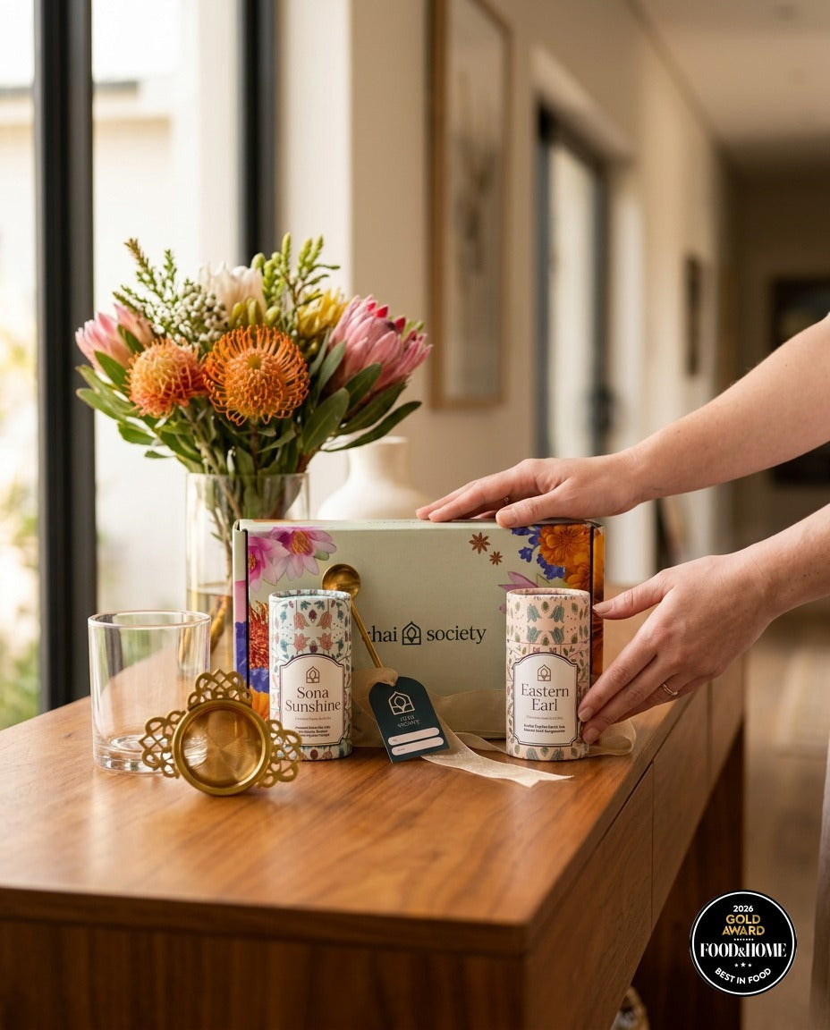 Chai Society tea gift box handed over beside a vase of proteas
