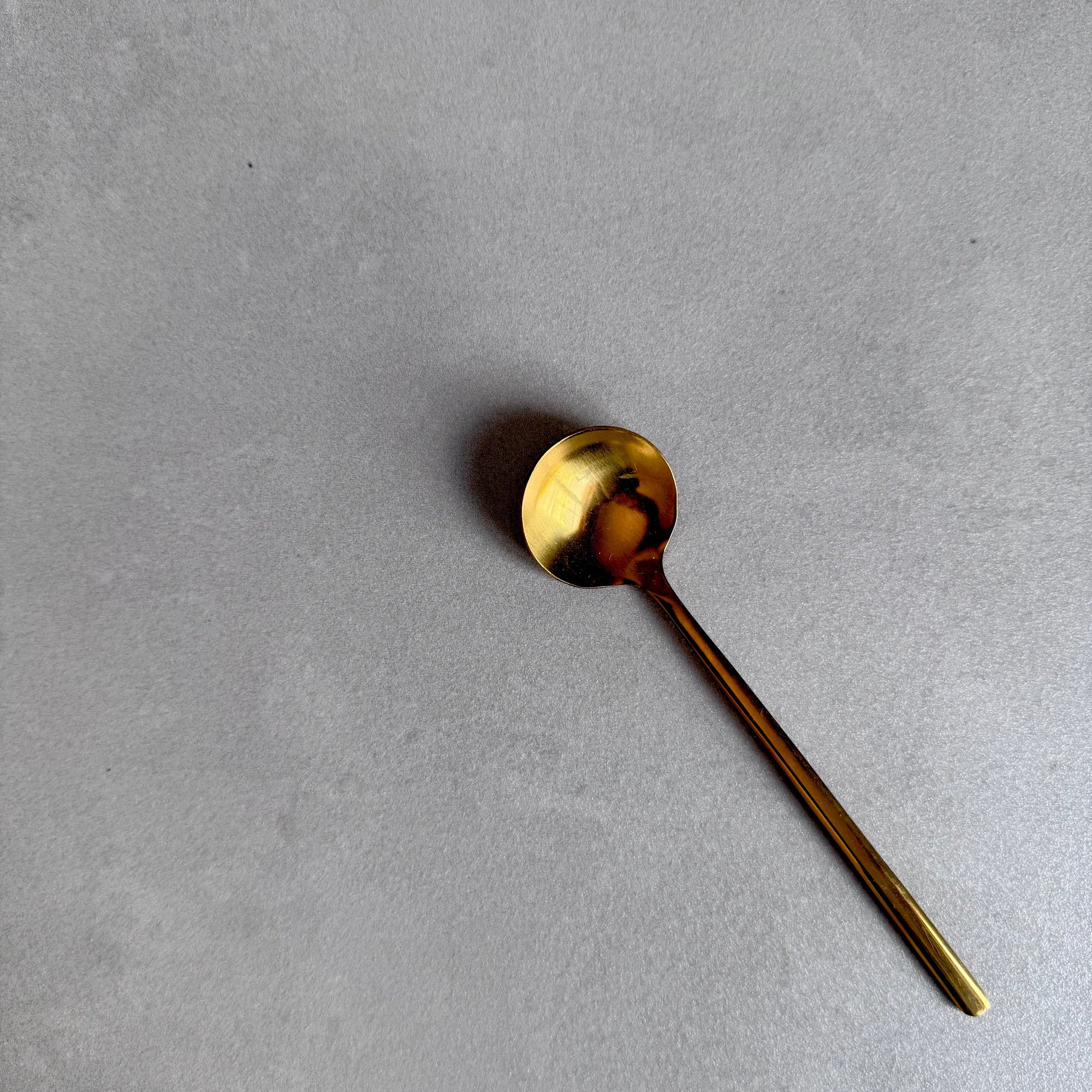 Elegant gold tea spoon on a gray background for loose-leaf tea rituals and premium tea gifting.