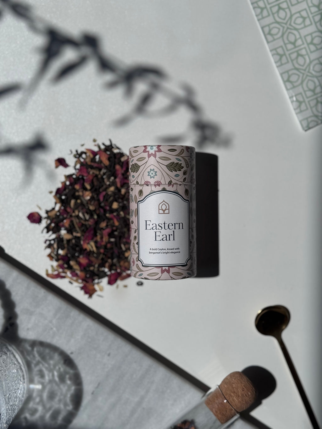 Tea packaging labeled 'Eastern Earl' with loose tea leaves on a light surface.