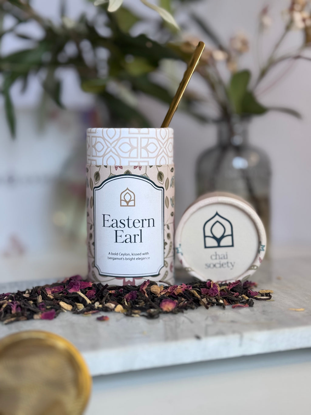Tea packaging with 'Eastern Earl' on a marble surface with tea leaves.