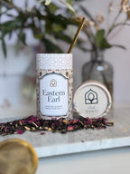 Tea packaging with 'Eastern Earl' on a marble surface with tea leaves.